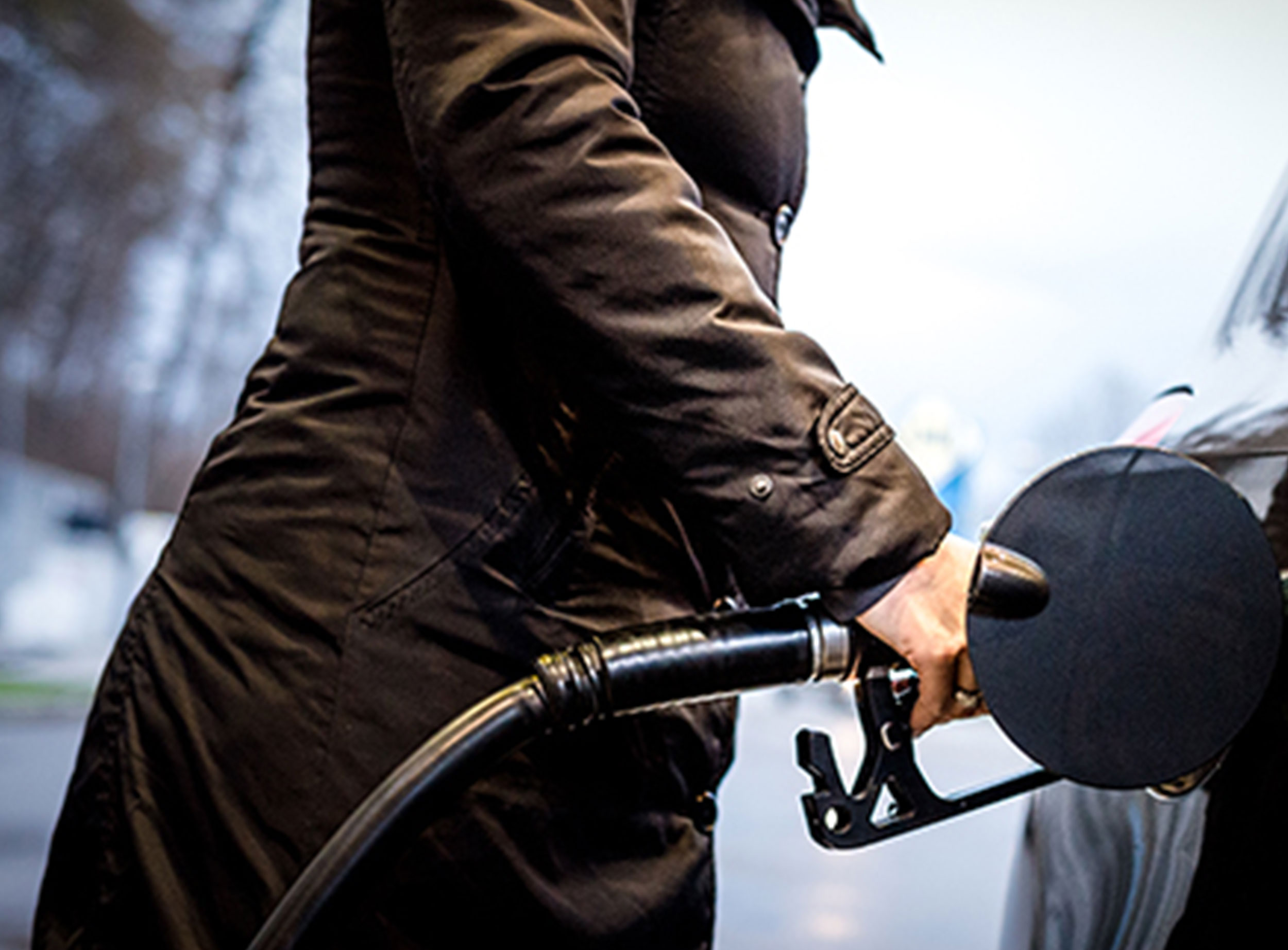 image of woman in coat pumping gas into vehicle
